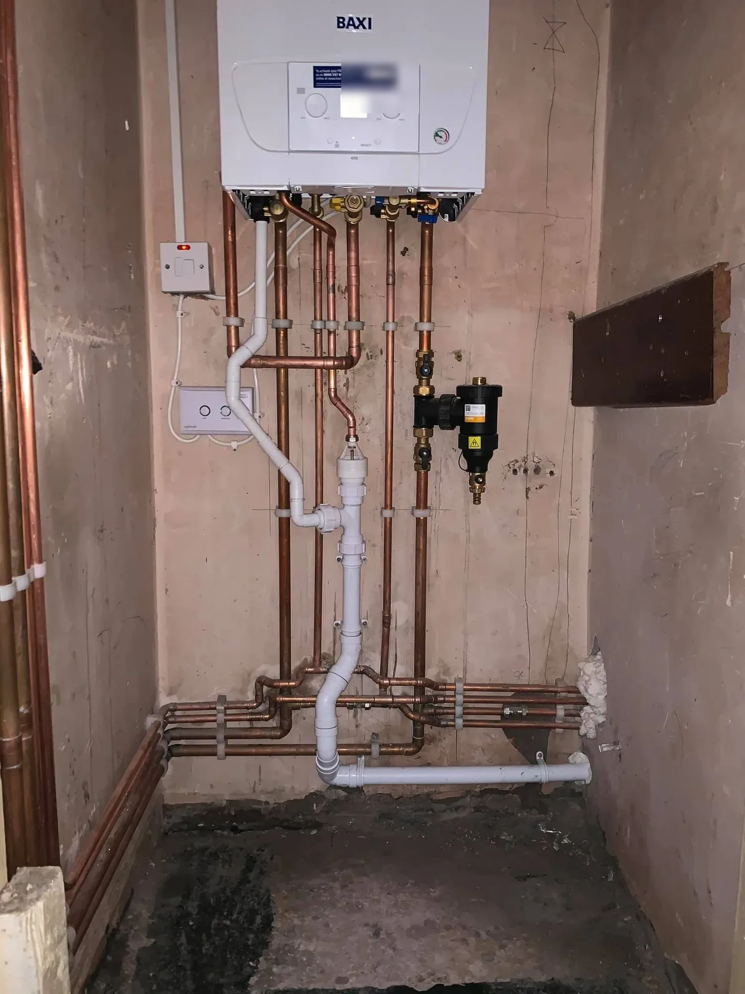 Baxi combi boiler fitted in a cupboard with neat copper pipework and a magnetic dirt separator