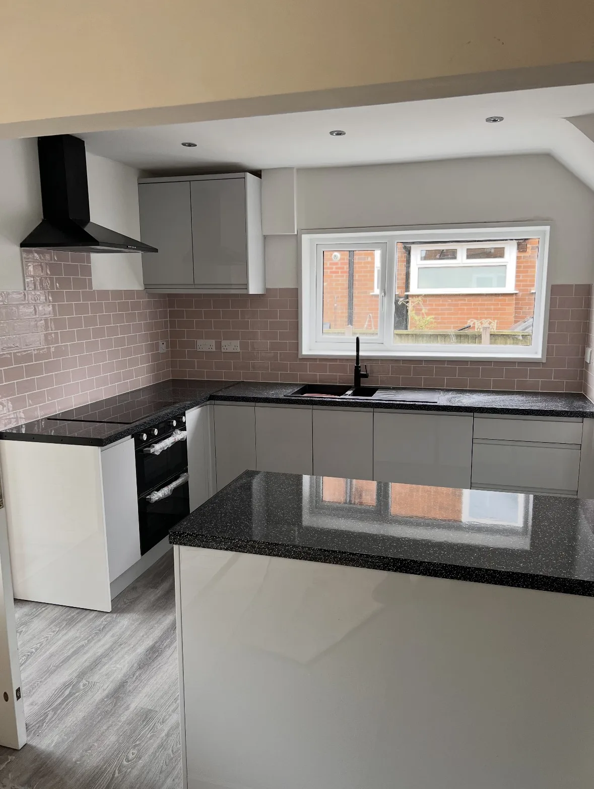 Light grey gloss kitchen with black worktops and island fitted by RC Renovation